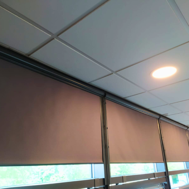 Biurowe wnętrze z roletami w kasecie w kolorze szarym.